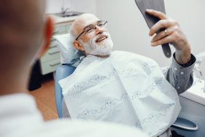 man in dental chair looking into a mirror and smiling